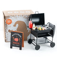 Bild in Galerie-Betrachter laden, Wichtel-Barbecue-Set mit Miniatur-Holzkohlegrill, Grillgut, Saucenflaschen und „Wichtelfreund Barbecue Grill Party“-Schild vor dekorativer Verpackung.