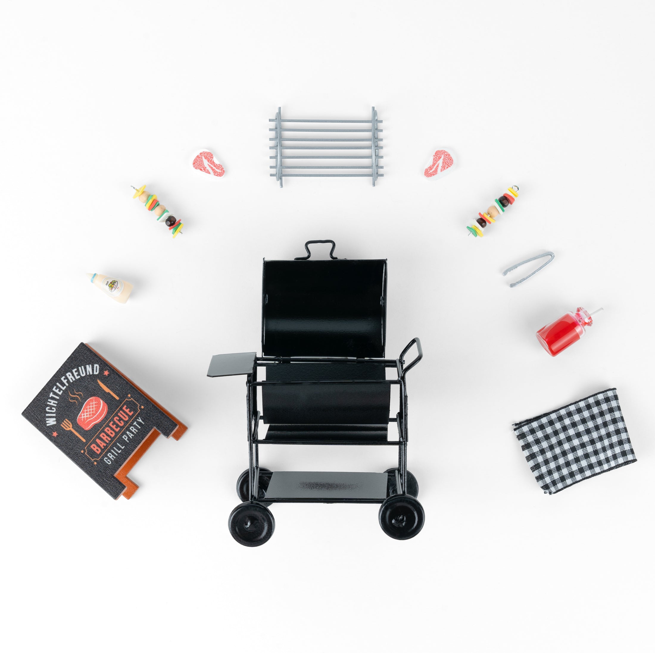 Wichtel-Barbecue-Set mit Miniatur-Holzkohlegrill, Grillutensilien und Essen. Enthält Grill, Spieße, Steaks, Grillzange, Saucen und kariertes Küchentuch.